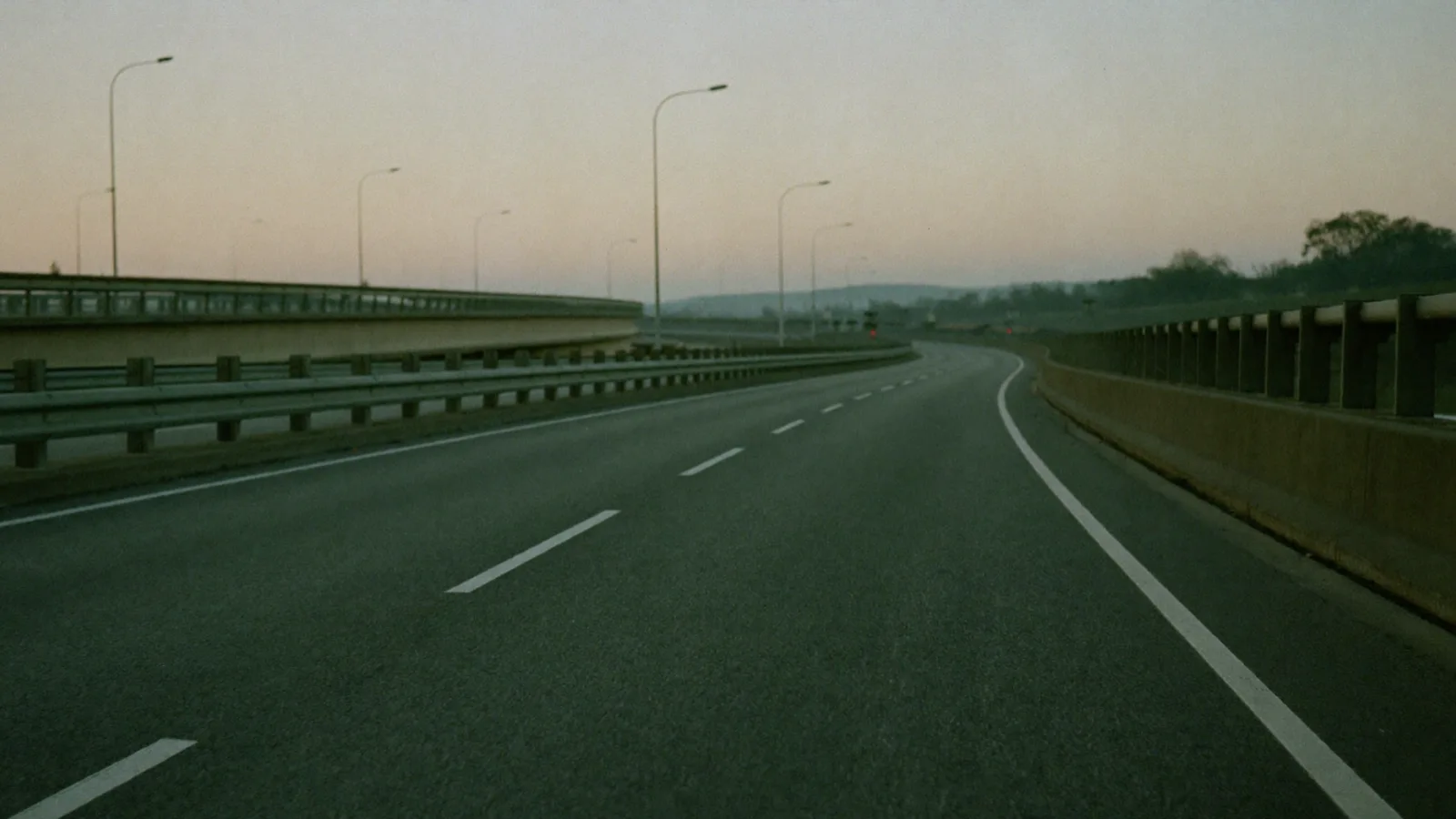 Autostrada vuota all'alba con guardrail e lampioni